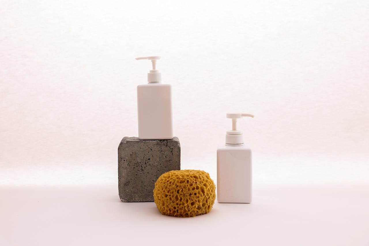 Simple arrangement of skincare dispensers and sponge against a white background, creating a minimalist look.